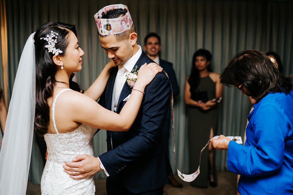 Bride dances with groom who wears a crown made out of fifty sterling pound notes during filipino wedding tradition