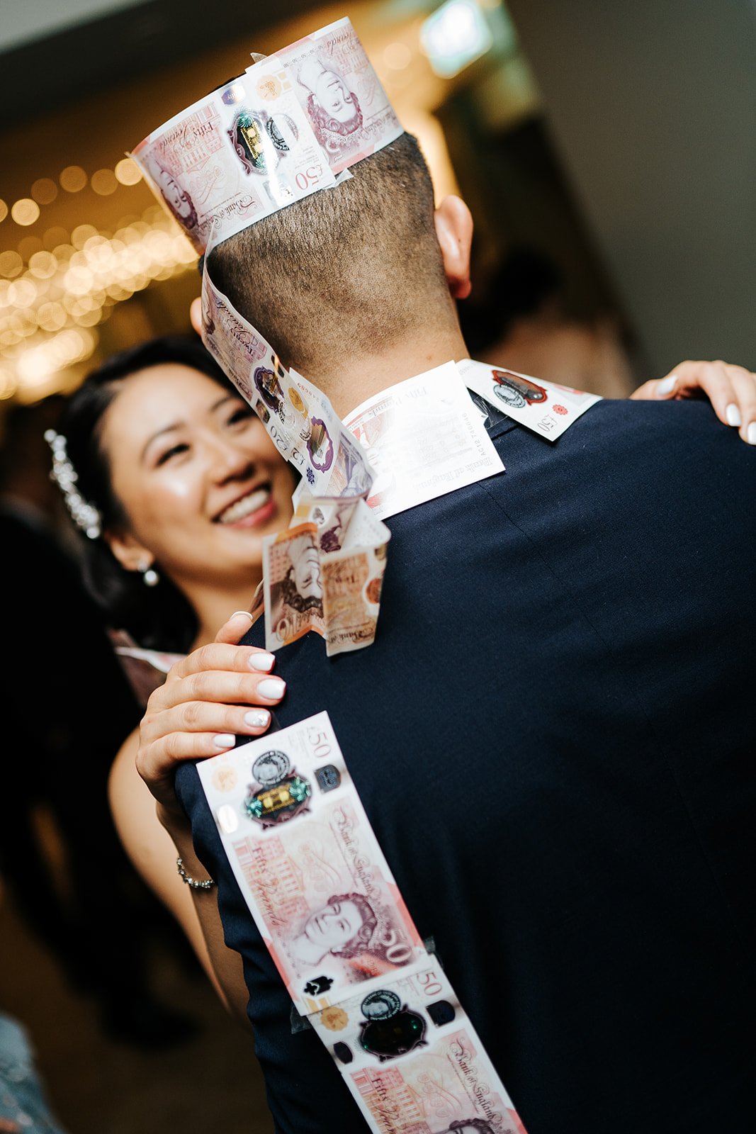 Bride dances with groom who wears a crown made out of fifty sterling pound notes during filipino wedding tradition