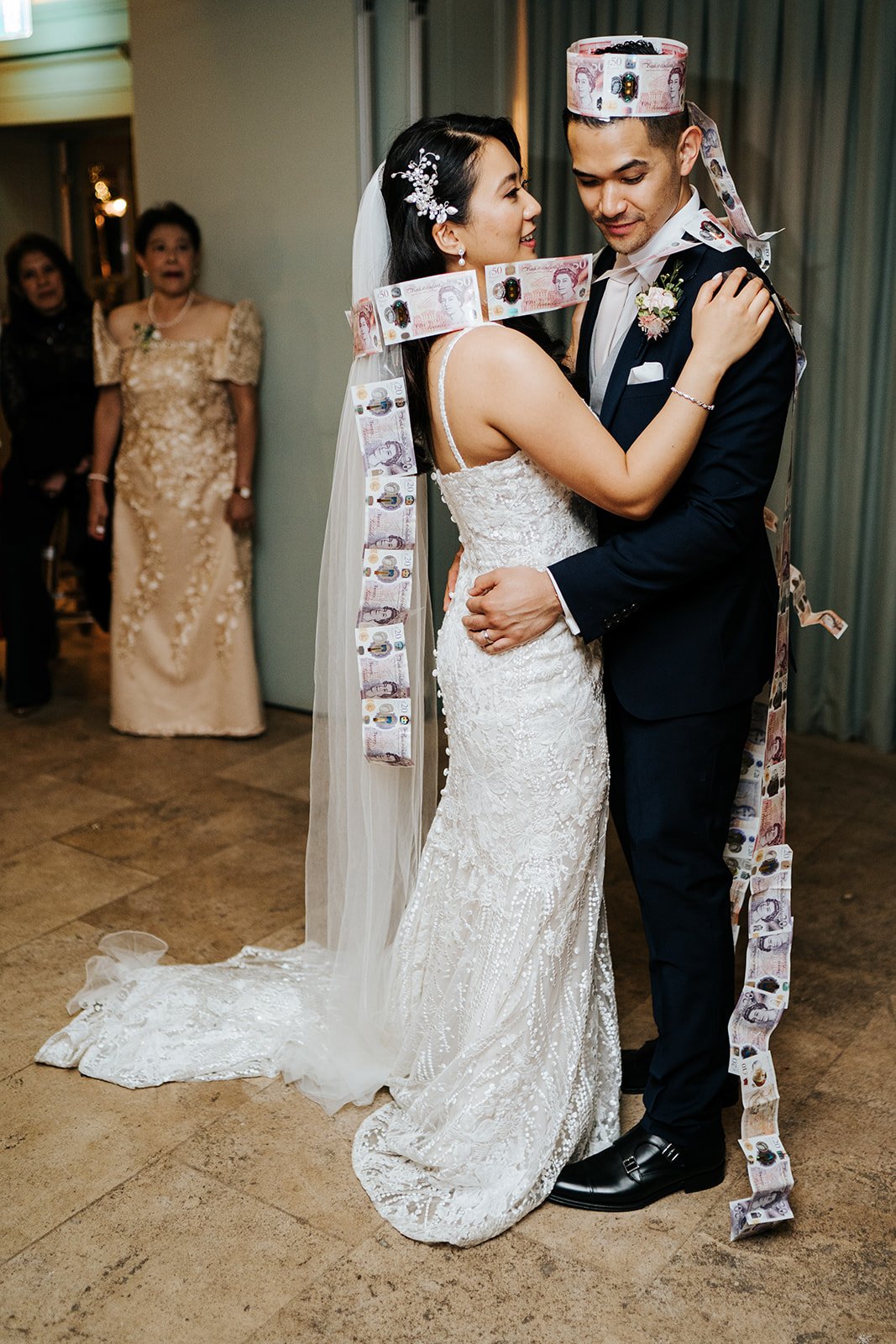 Bride dances with groom who wears a crown made out of fifty sterling pound notes during filipino wedding tradition