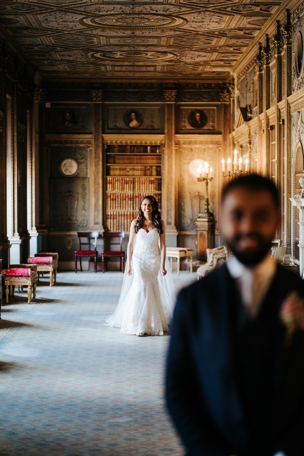 Bride, in beautiful white dress, walks up to groom in Long Gallery at Syon Park wedding for first look