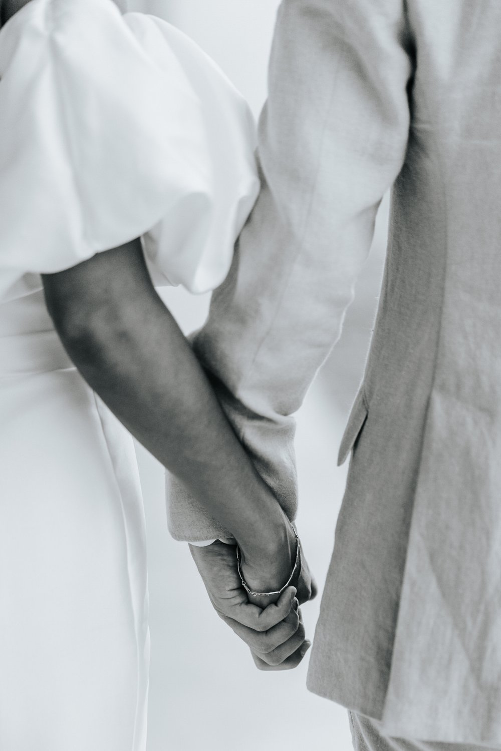 Close-up black and white photo of bride and groom holding hands