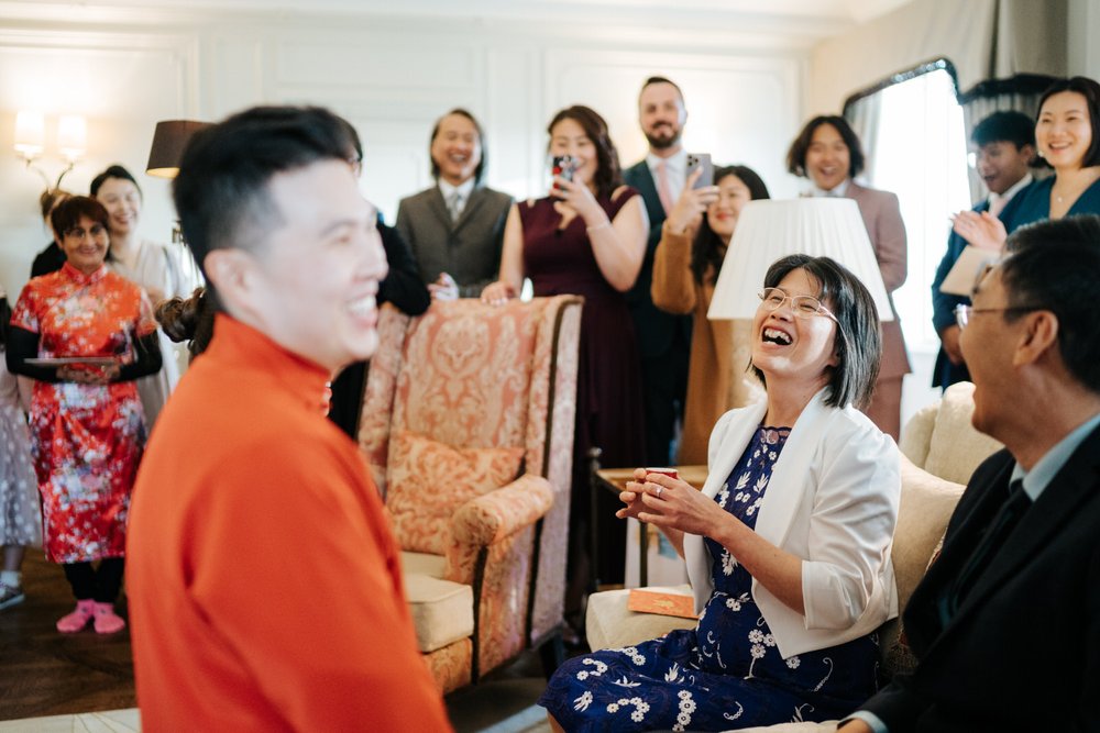 Groom, dressed in traditional garment, smiles at his mother during Chinese tea ceremony at The Dorchester in London