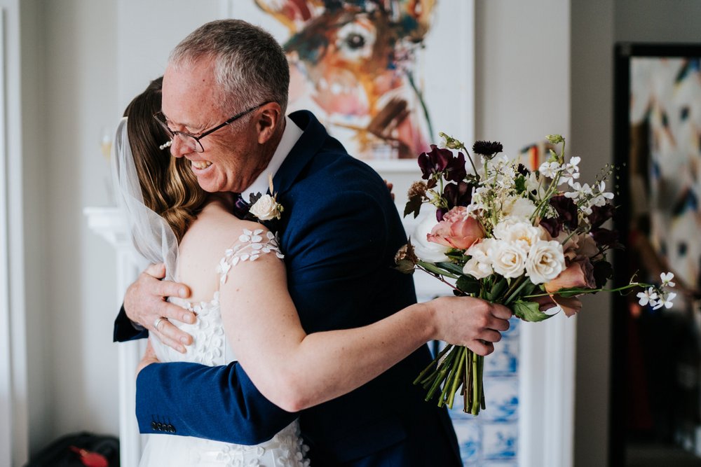 Father of the bride hugs bride after seeing her in her wedding dress for the first time at Richmond Harbour Hotel wedding prep