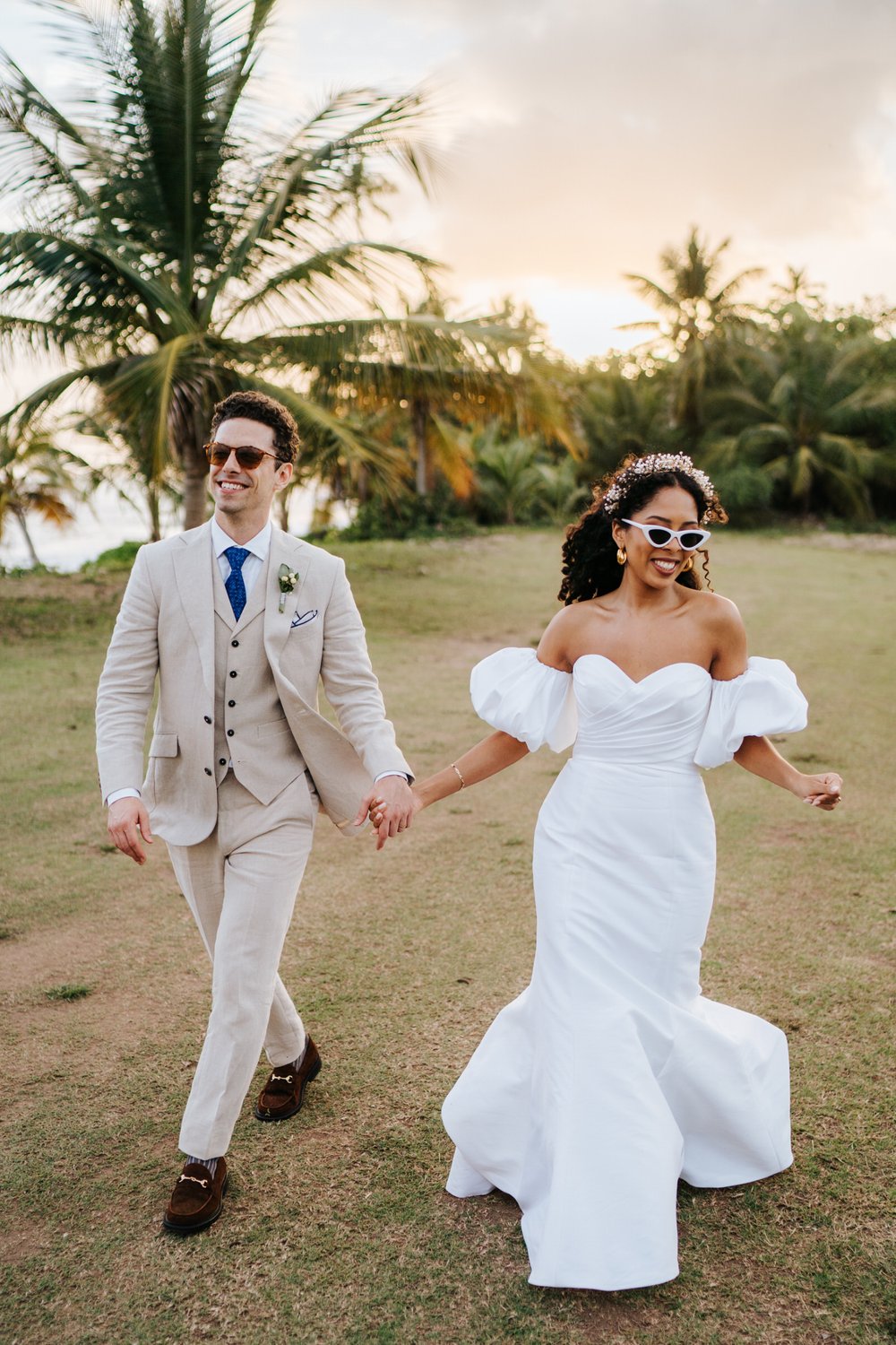 Bride and groom, wearing fashionable shades, strut towards camera in Puerto Rico beachfront wedding in Vieques