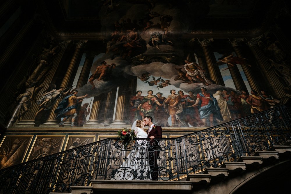Bride and groom pose in grand staircase at Hampton Court Palace wedding
