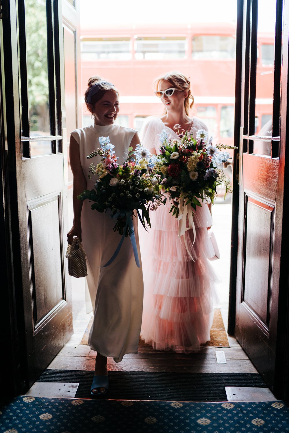 Bride wearing pink dress is accompanied into York House by bridesmaid before wedding ceremony 