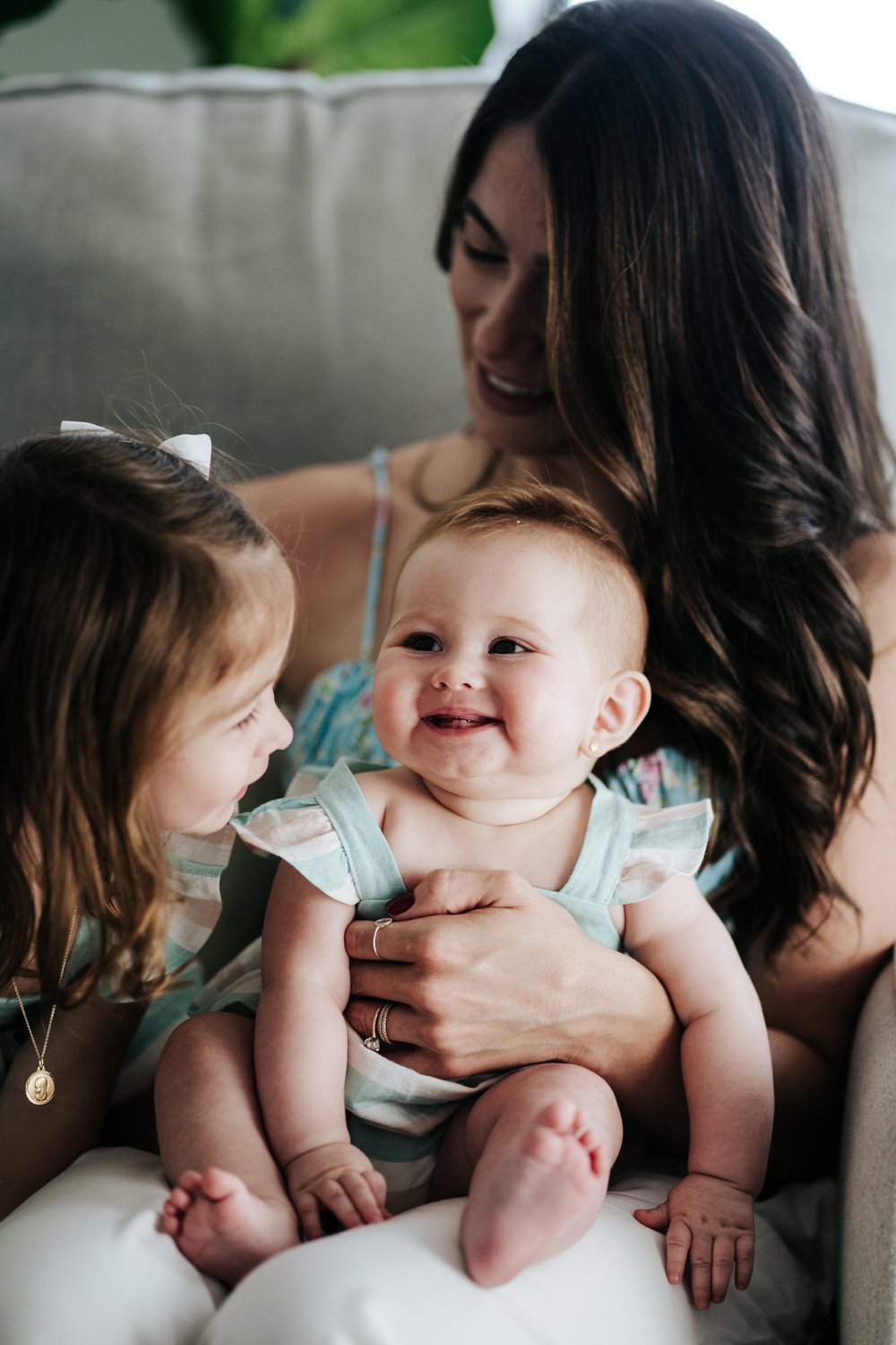 Baby smiles as it poses with sister and mother during family shoot