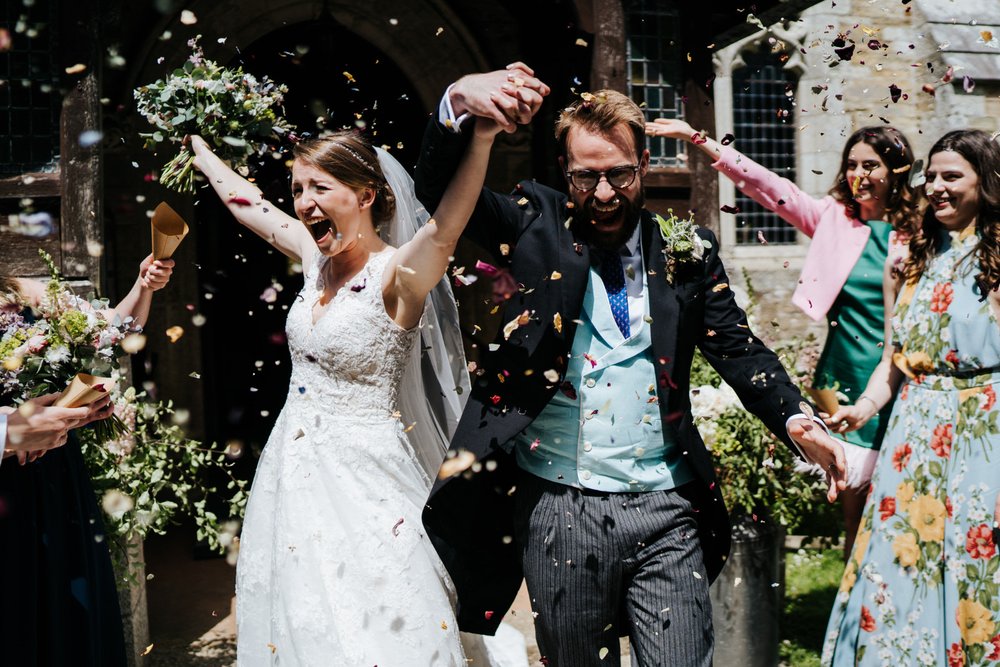 Bride and groom exit church in Falmouth wedding ceremony as everyone throws confetti at them
