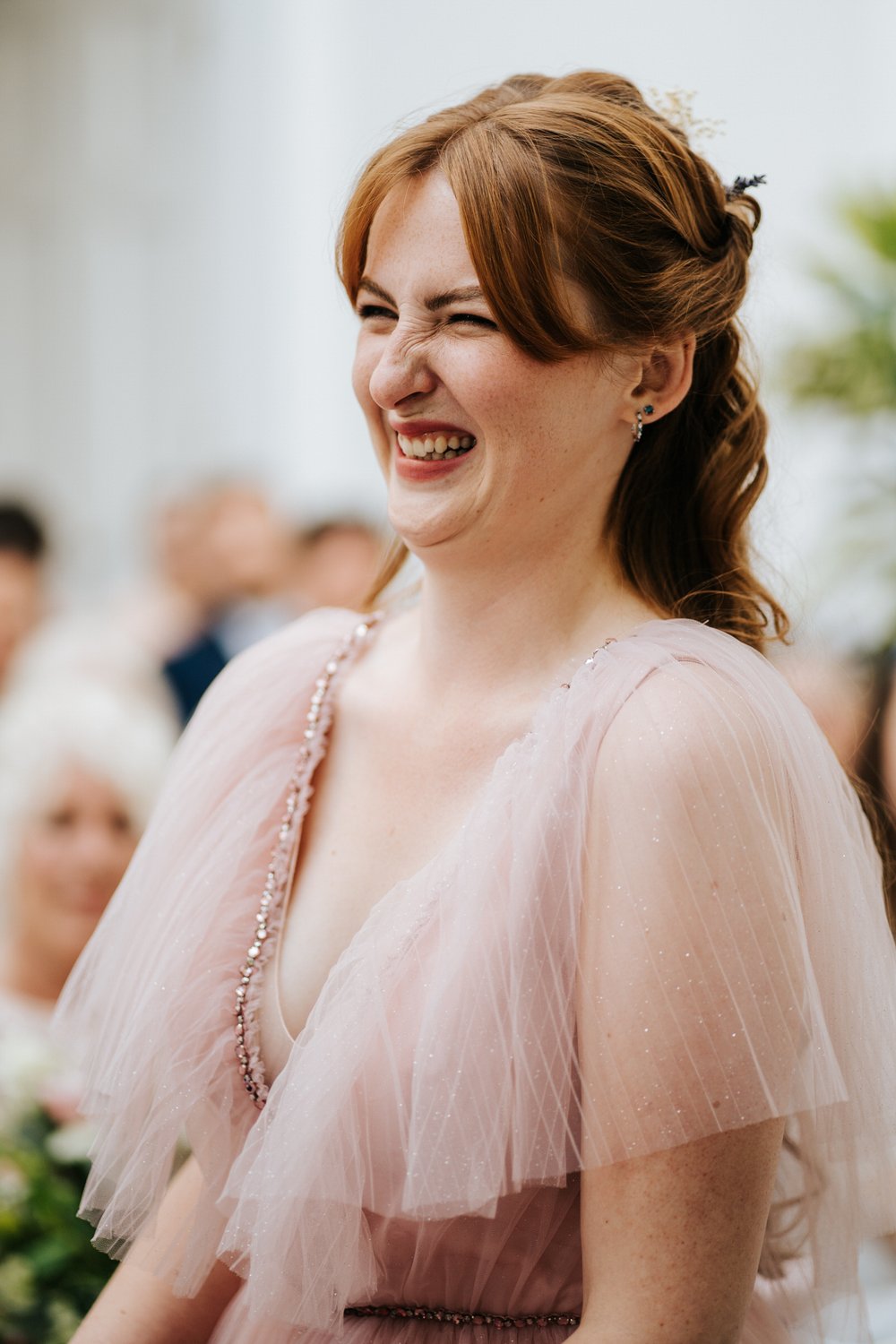 Bride wearing pink dress smiles and smirks in close-up photograph during wedding ceremony at York House