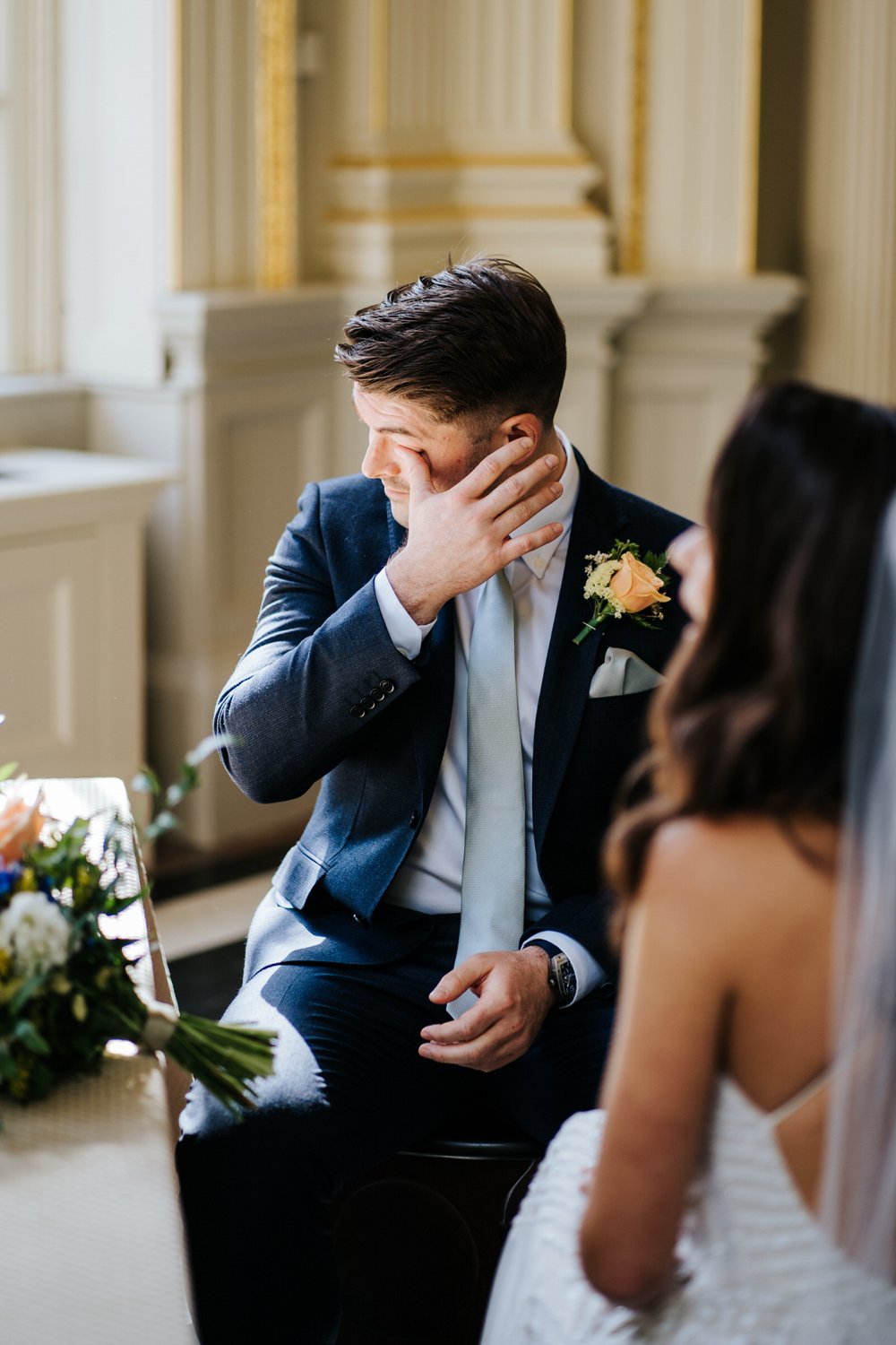Groom wipes a tear of his eye as he sits during Orleans House Gallery wedding ceremony
