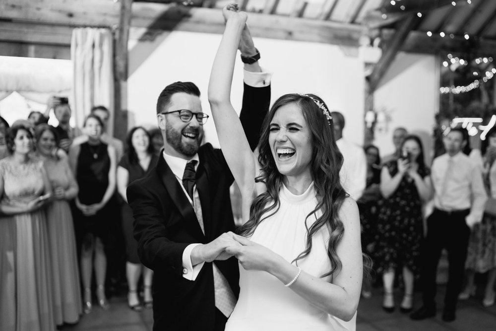 Black and white photo of bride and groom sharing their first dance and twirling at Chenies Manorhouse wedding 