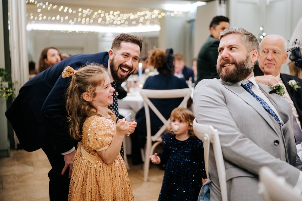 Little girl laughs as groom turns around seconds after she blew bubbles in his face at Bingham Riverhouse wedding