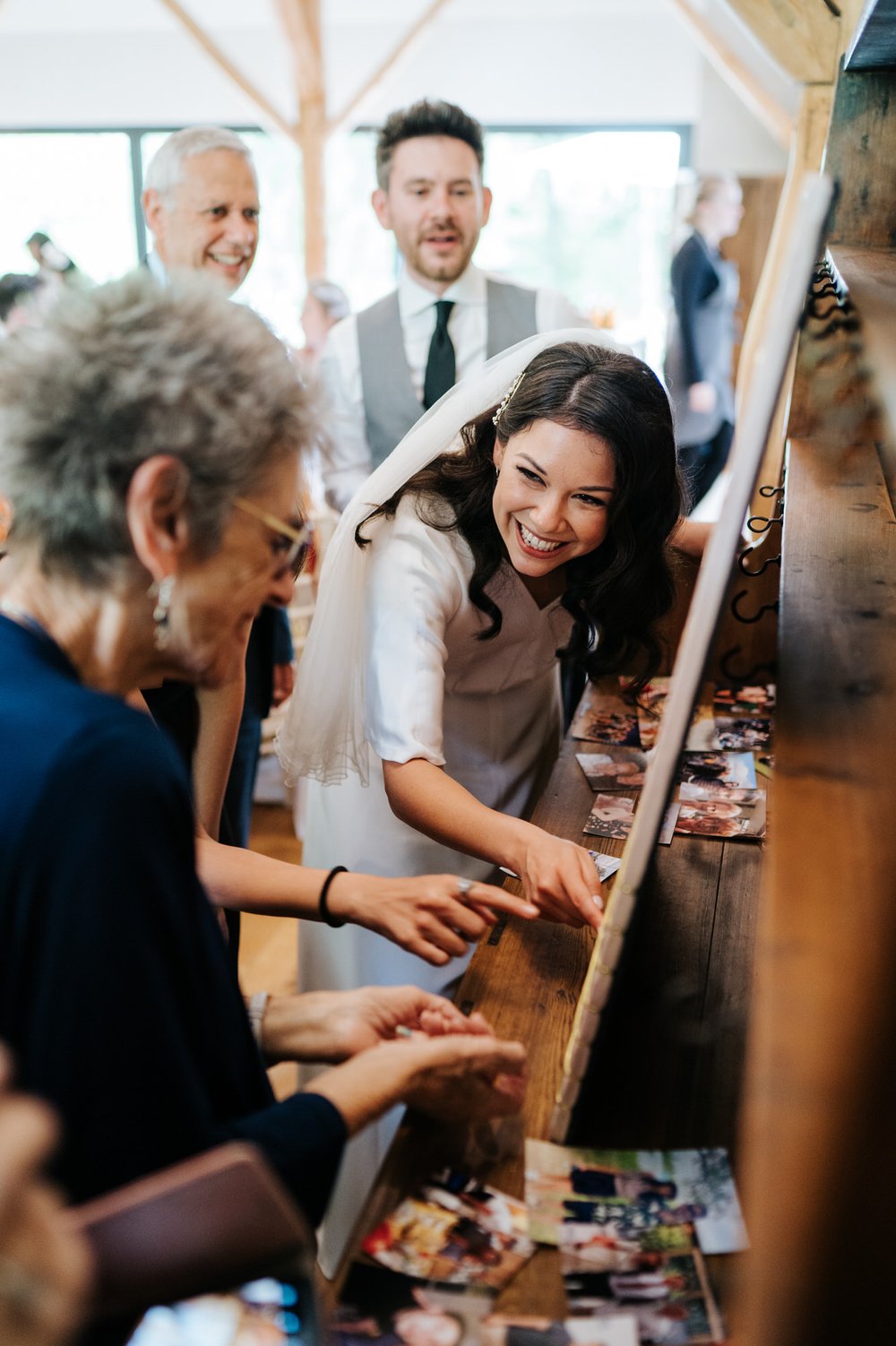 Bride points out relative on pinboard to elderly grandmother as they both smile