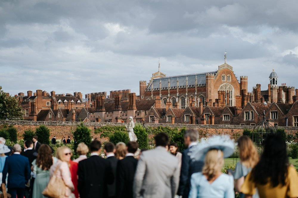 Atmospheric photograph of Hampton Court Palace's many chimneys as guests, front and out of focus, walk towards it