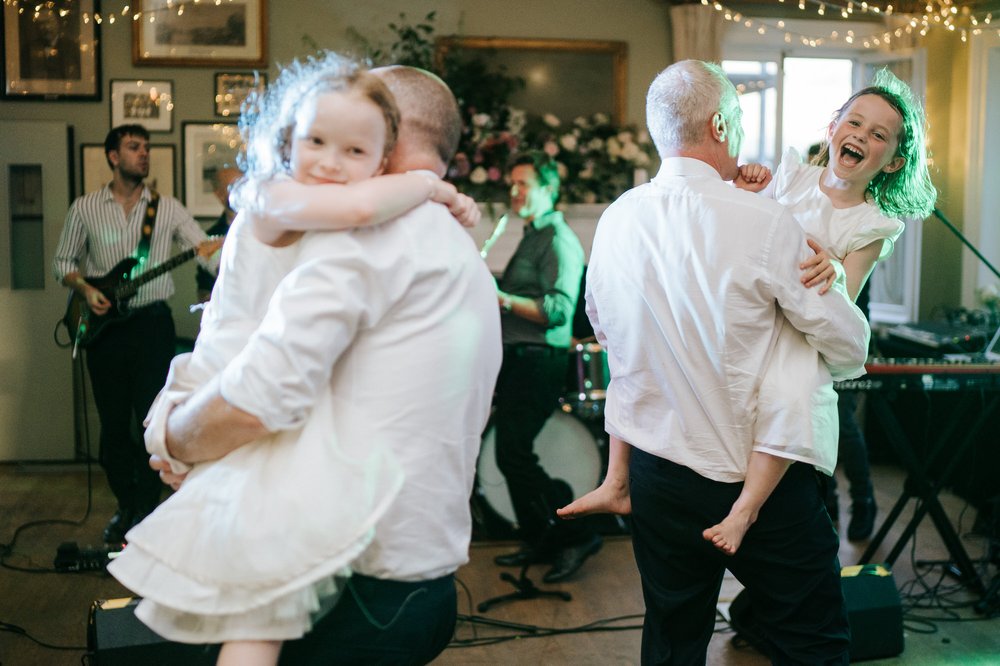 Two dads dancing with their daughters on the dancefloor during Putney Rowing Club ceremony