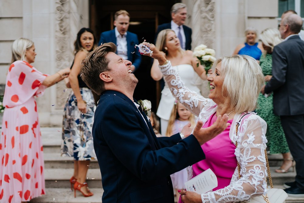 Groom is startled by his mother pelting him with confetti in front of Wandsworth Town Hall once it had seemingly all ended