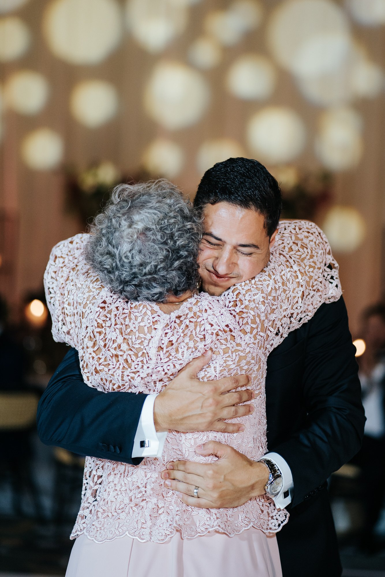 Groom hugs his mother tightly after they share first dance