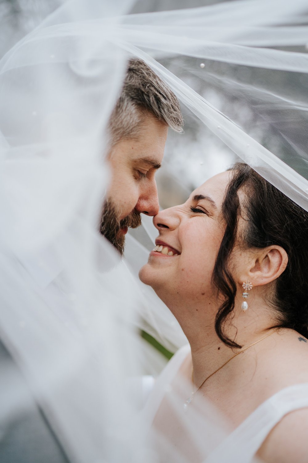 Close-up image under veil as bride and groom nuzzle and smile at Bingham Riverhouse wedding