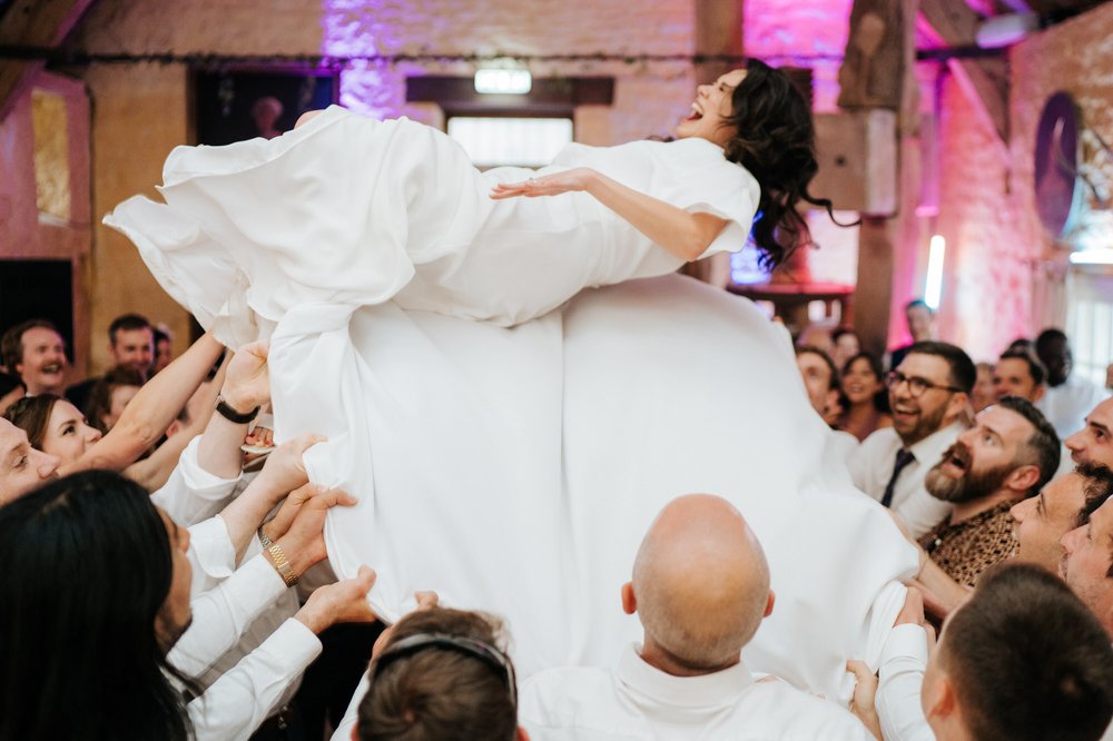Bride is thrown in the air during Jewish dance at wedding