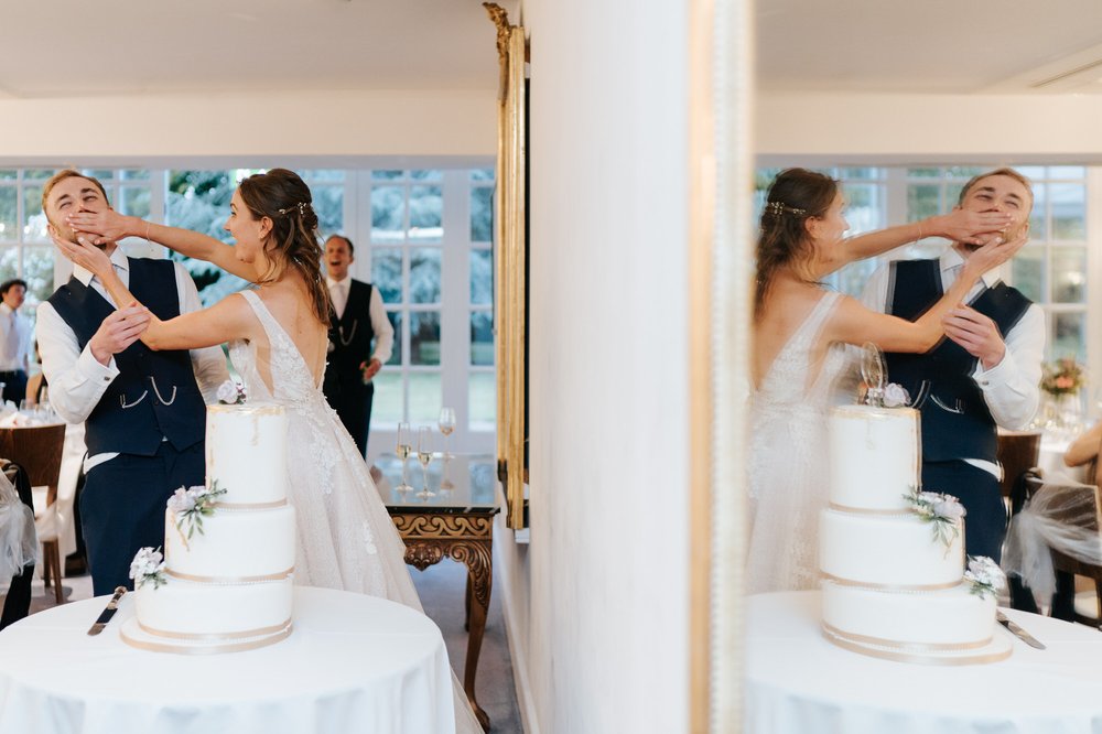 Bride shoves cake in groom's face during Hampton Court Palace Green Room wedding