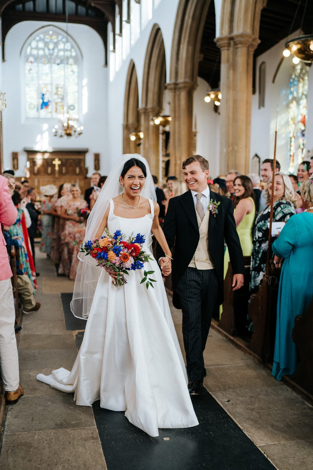 Bride and groom smile as they exit the church they just got married in, both smiling