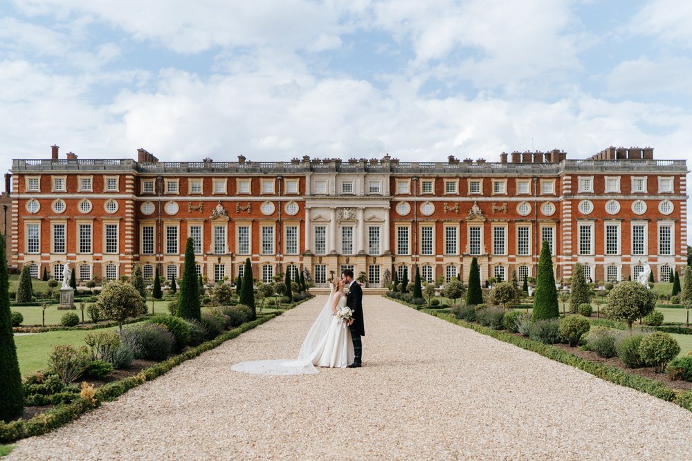 Epic photograph of bride and groom posing in front of Hampton Court Palace