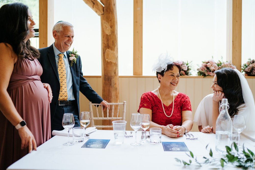 Bride and her family talk around head table and smile at each other 