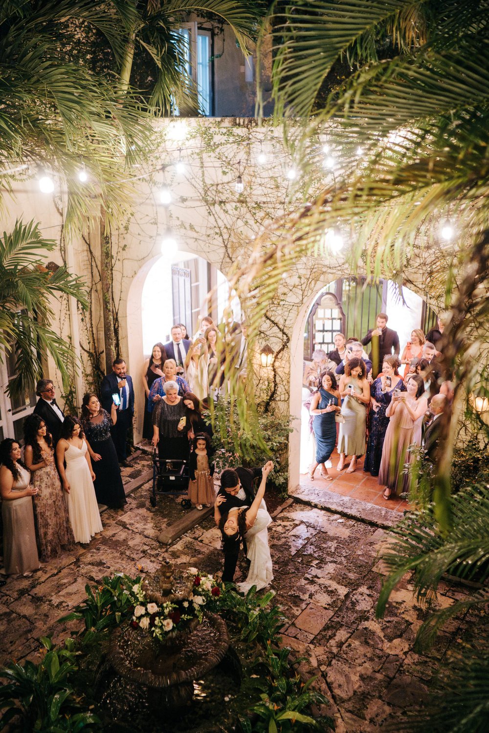 Groom dips bride during first dance in wide photograph taken from second floor