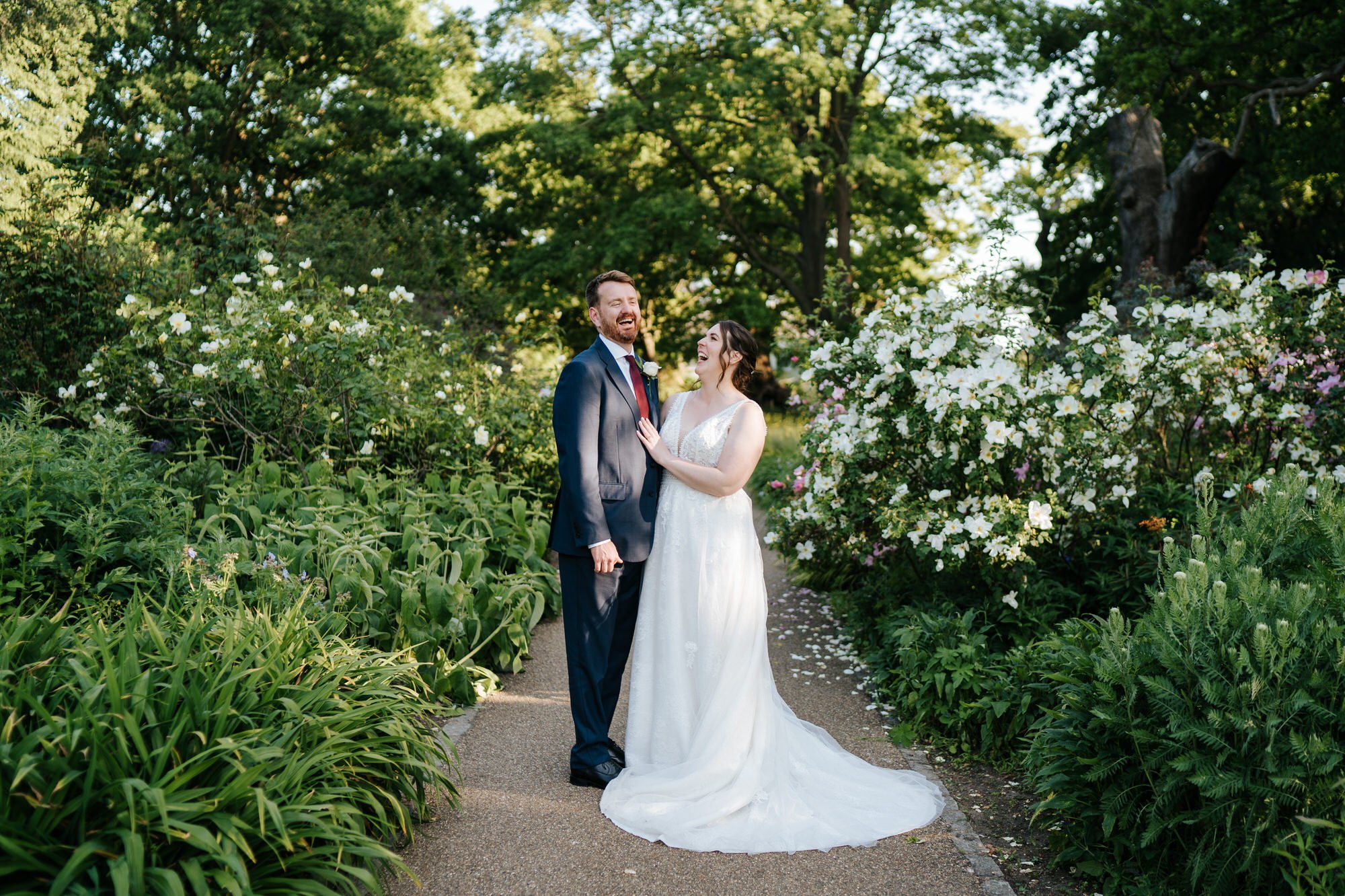 Bride and groom take a second to laugh in dappled light during couples photos taken at Pembroke Lodge in Richmond
