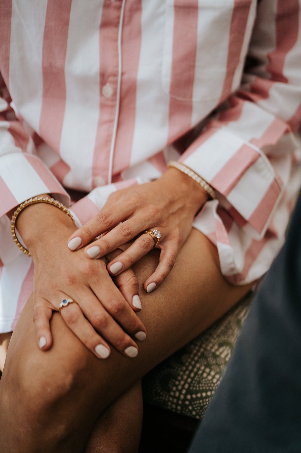 Bride sits in her striped robes and crosses her hands on her lap, with her engagement ring clearly visible