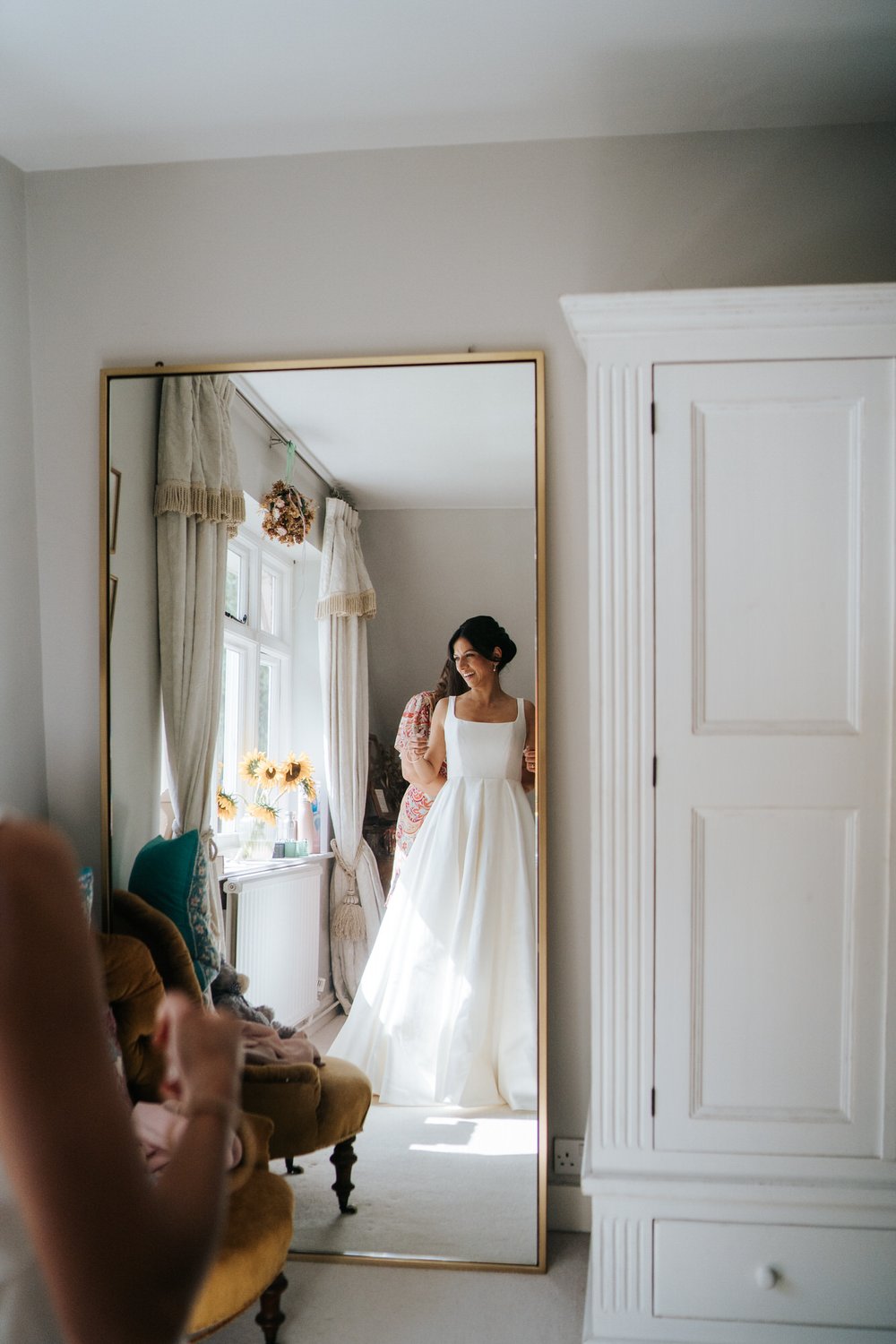 Bride, in her wedding dress, looks at herself in the mirror