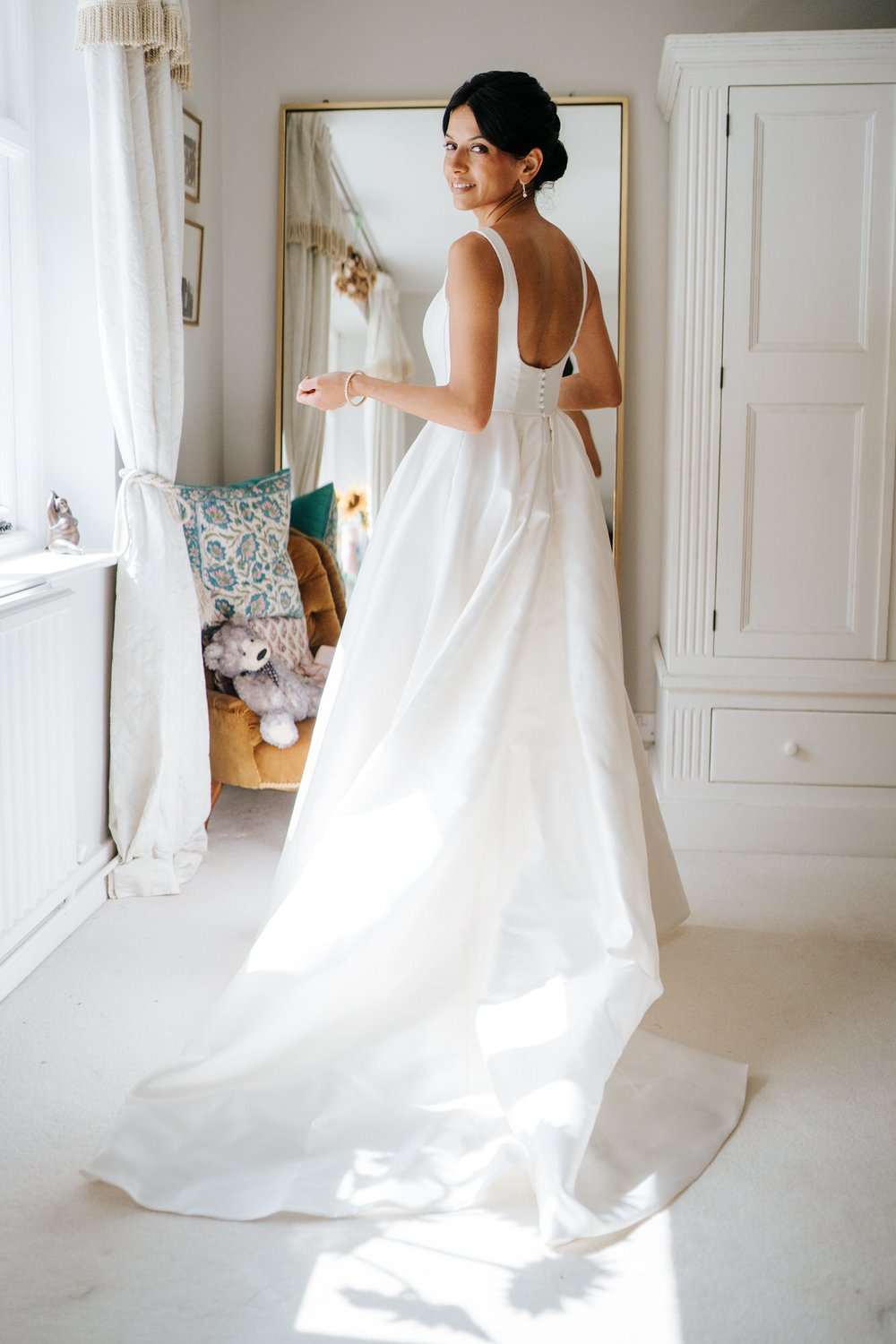 Bride, in her wedding dress, looks over her shoulder and back at camera in candid portrait