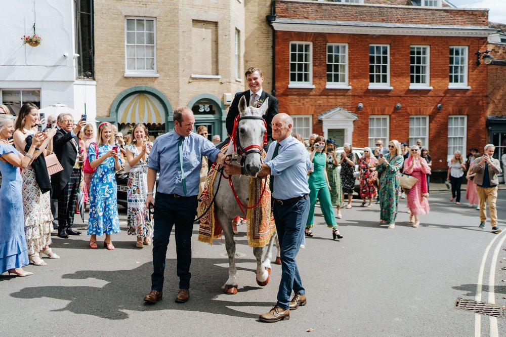 Groom is seen riding a horse during wedding day baraat in Woodbridge