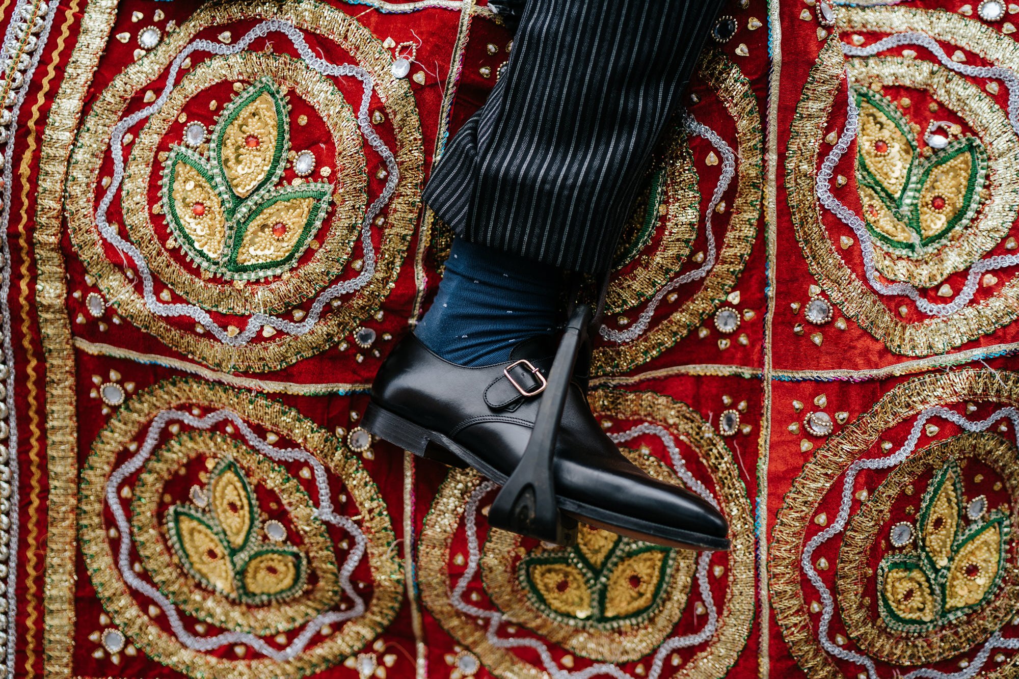 Groom's shoe seen in horse tack as it rests against colourful decoration 