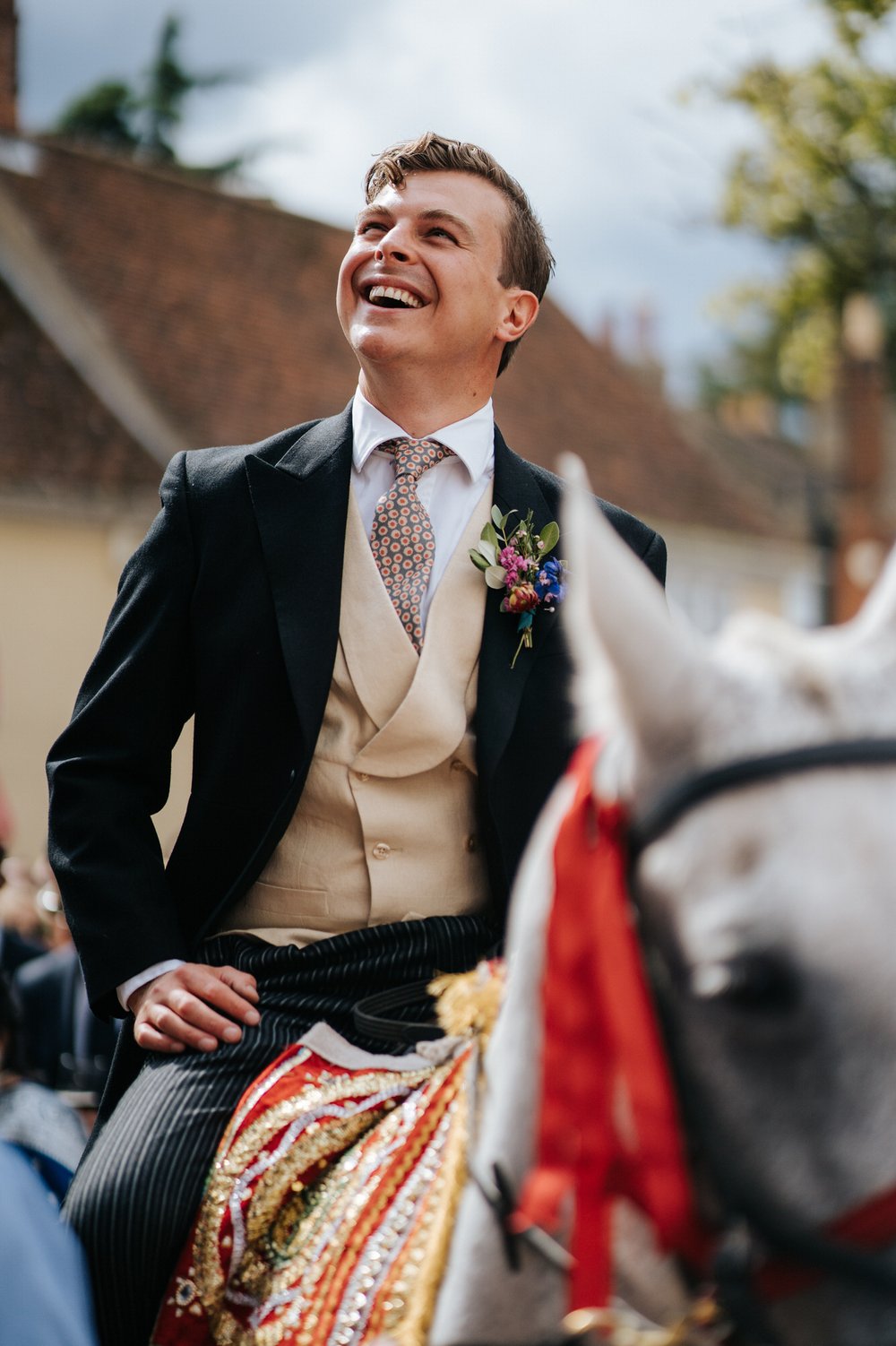 Groom is joyful and excited as he sits on lavishly decorated horse during wedding day baraat