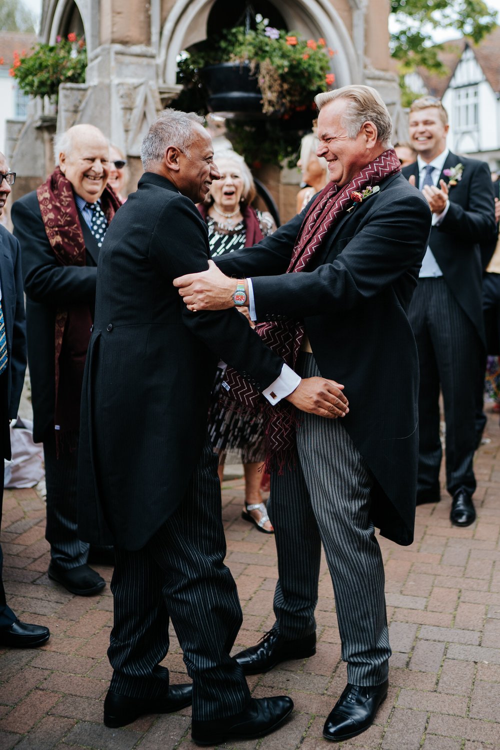 Groom and bride's fathers embrace during wedding day baraat in Woodbridge