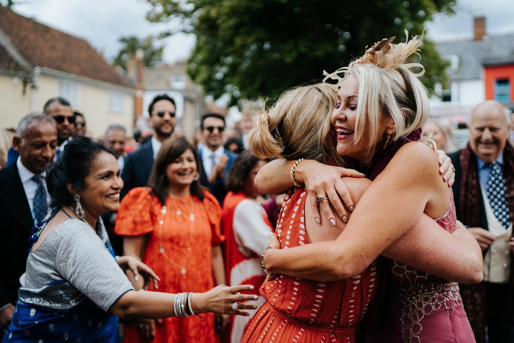 Bride's aunt and groom's mother embrace during wedding day baraat