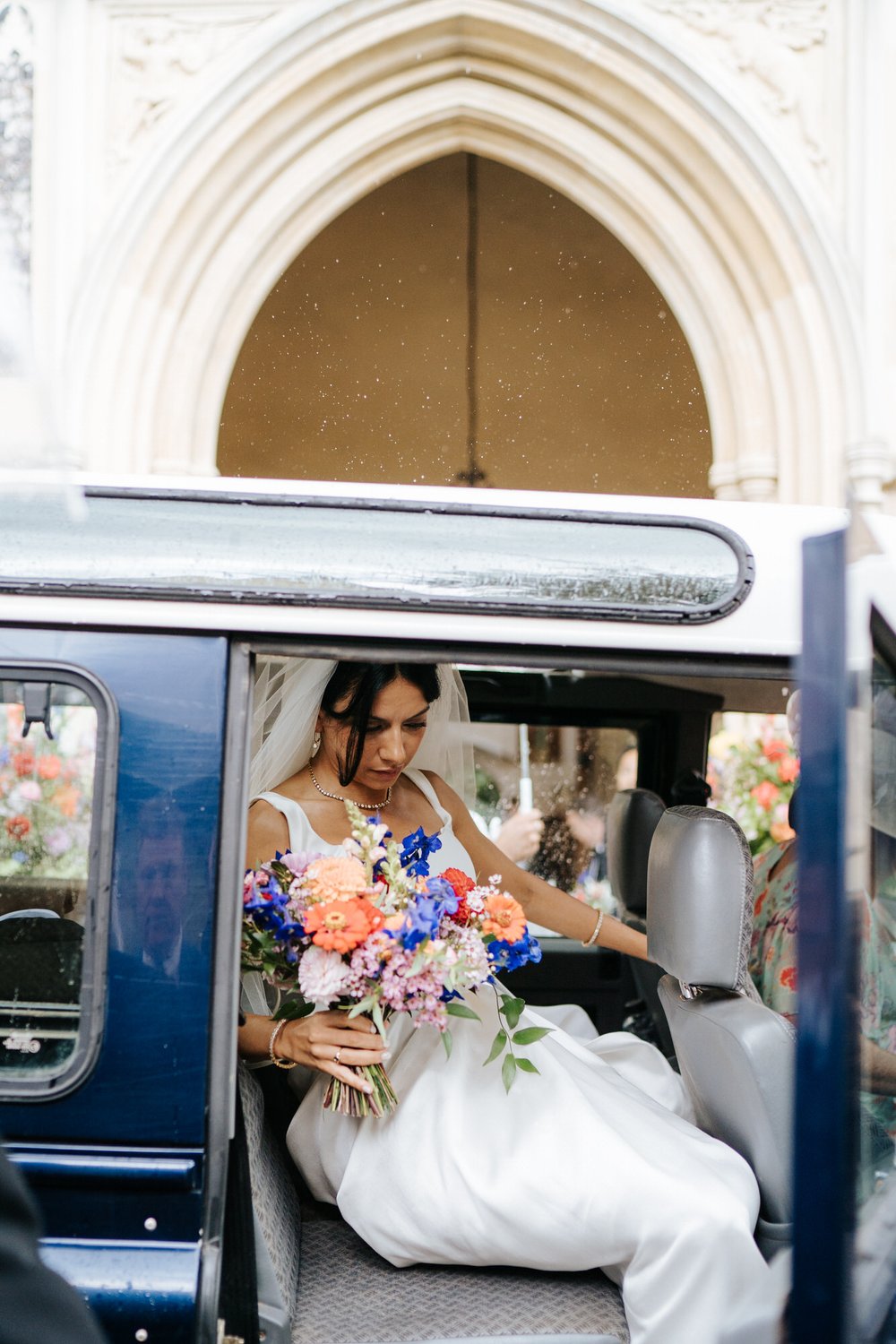 Bride arrives at church in Land Rover Defender and is seen exiting the vehile as rain drops pelt the rooftop