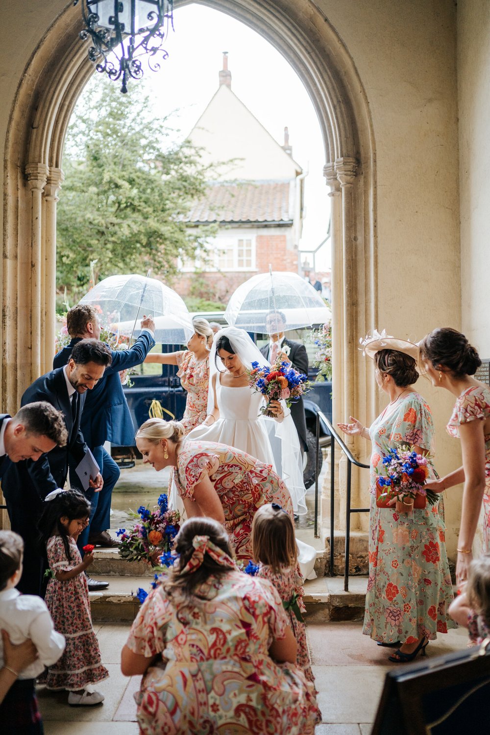 Bride, bridal party and relatives prepare to walk down the aisle as bride fluffs out her dress