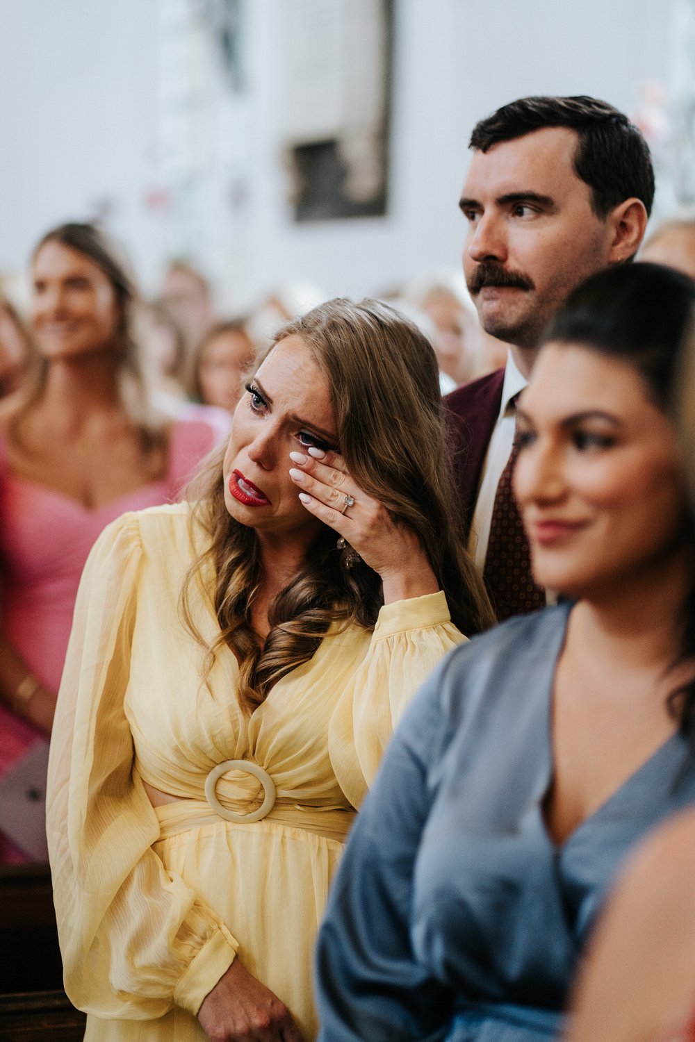 Guests wipes tear off her cheek as she sees the bride walking down the aisle