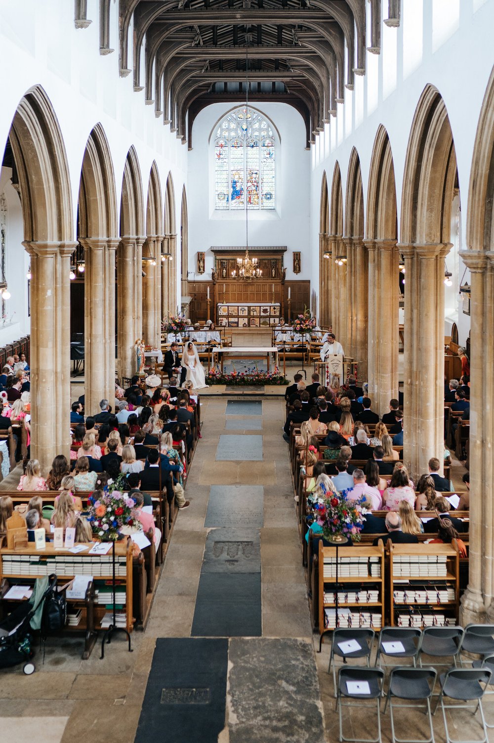 Wide photograph of the church featuring all the guests, pews and the couple