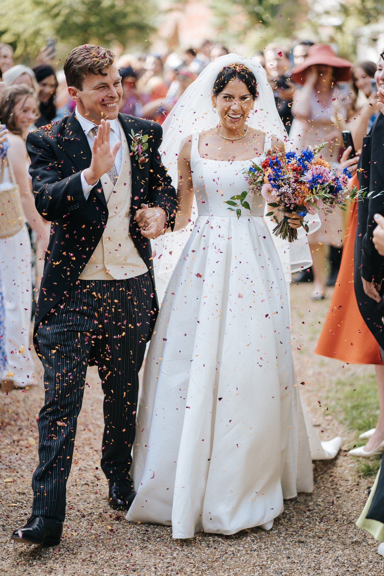 Bride and groom extremely joyful as they walk through a tunnel of confetti after exiting the church in Woodbridge