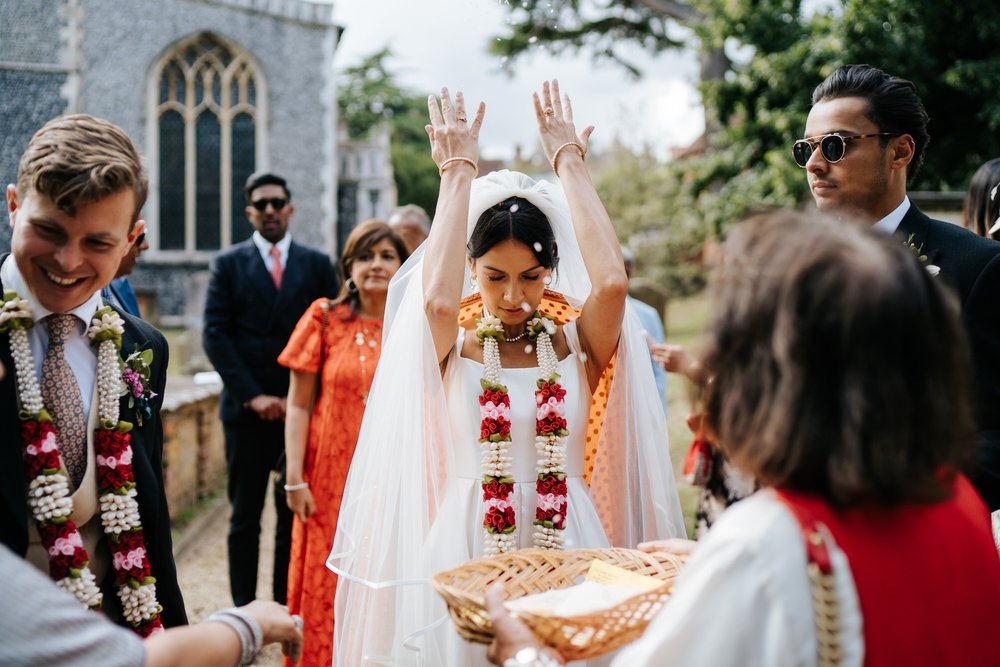 Bride throws rice over her shoulders before leaving the church grounds