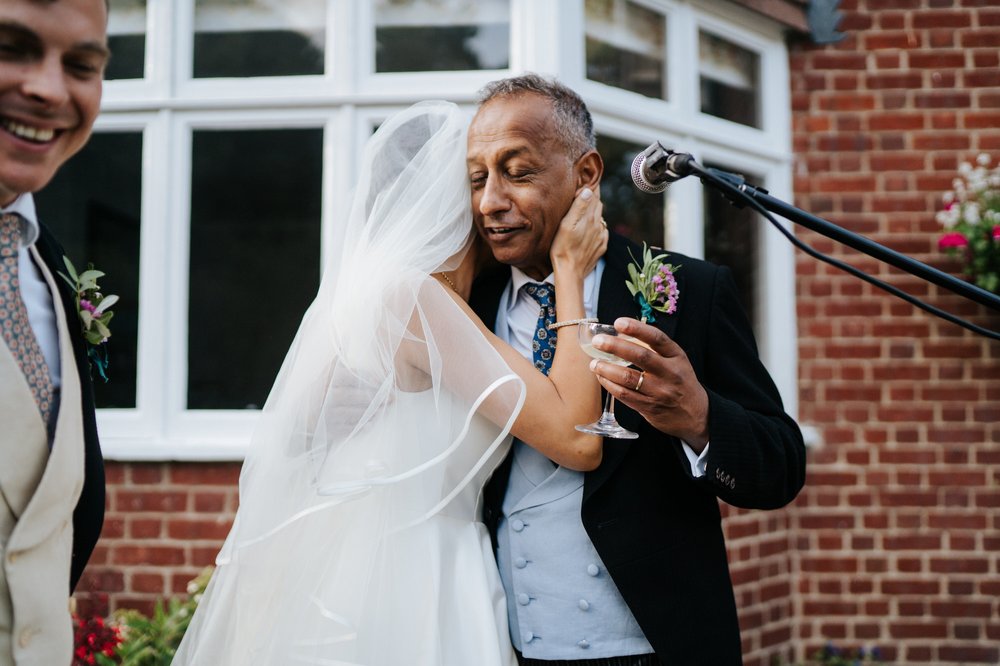 Bride embraces her dad after he finishes delivering his wedding speech