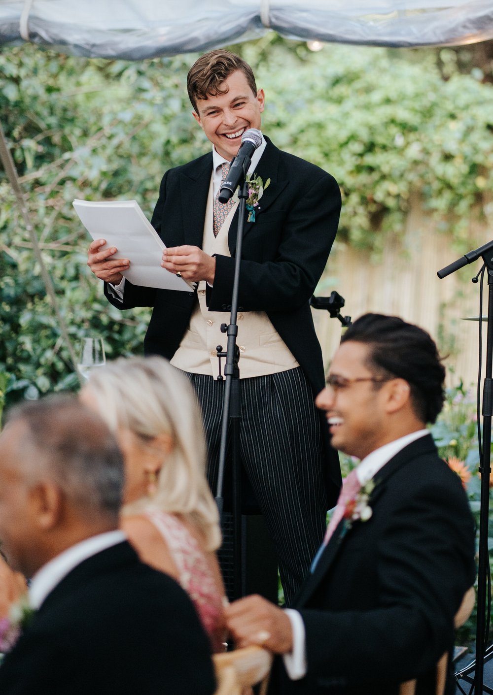 Groom smirks as he delivers passionate wedding speech inside marquee