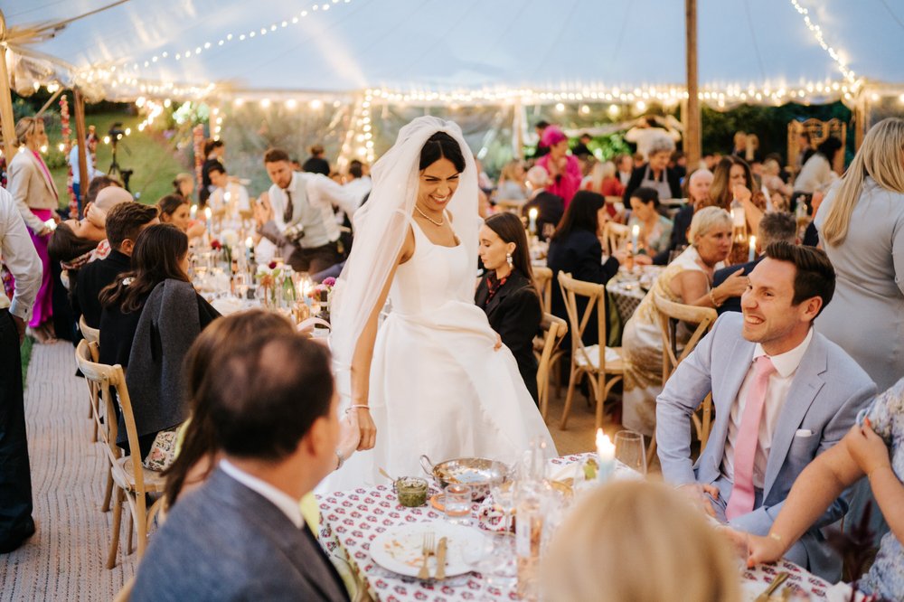 Bride walks around the marquee and says hello to some of her friends while they enjoy their meal