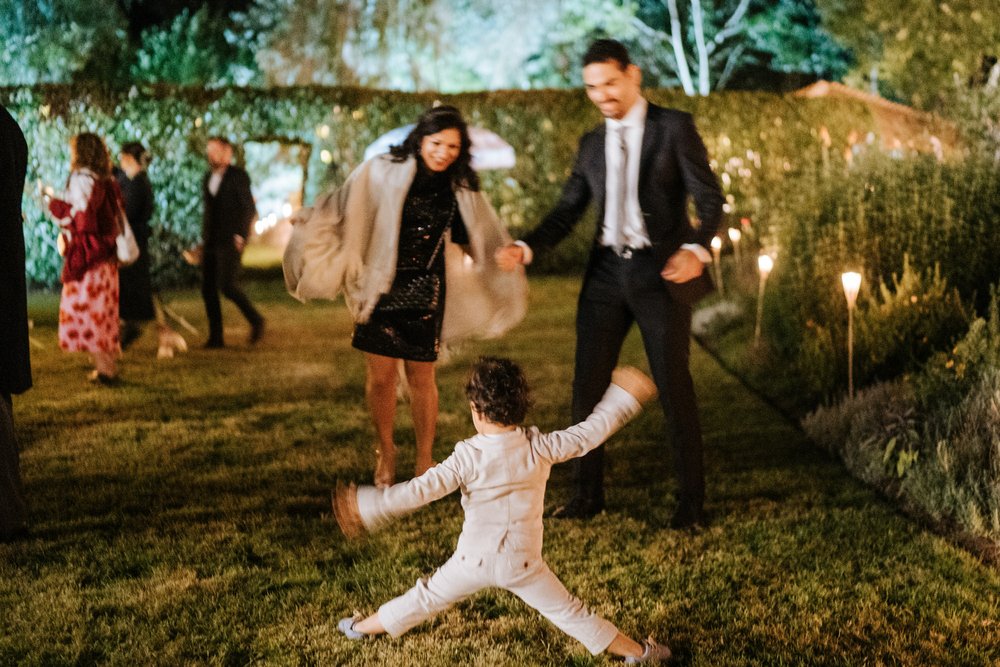 Two guests and their son play around the garden where the wedding is taking place