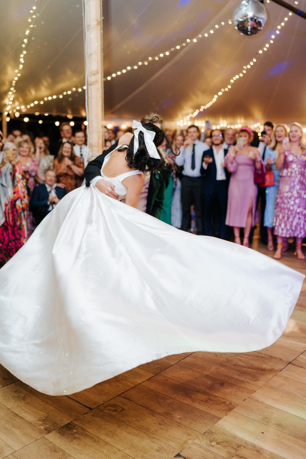 Bride's dress fans out naturally as groom has lifted her and is swirling her across the dancefloor