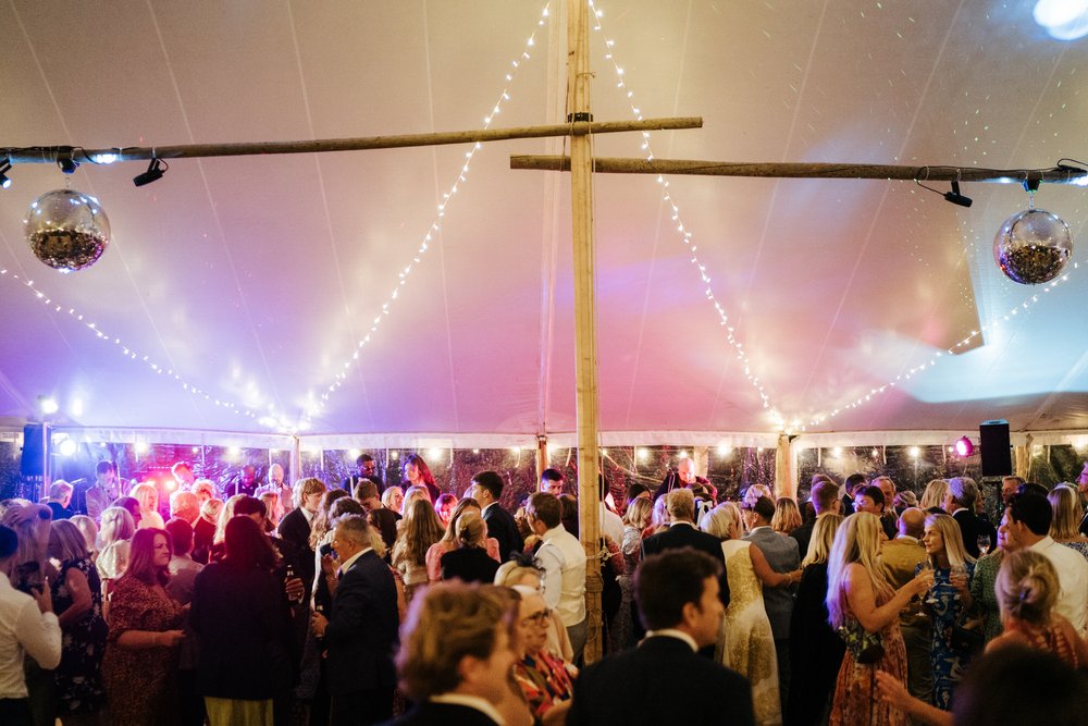 Wide atmospheric photograph of the dancefloor inside the marquee, lit beautifully by the DJ's lights