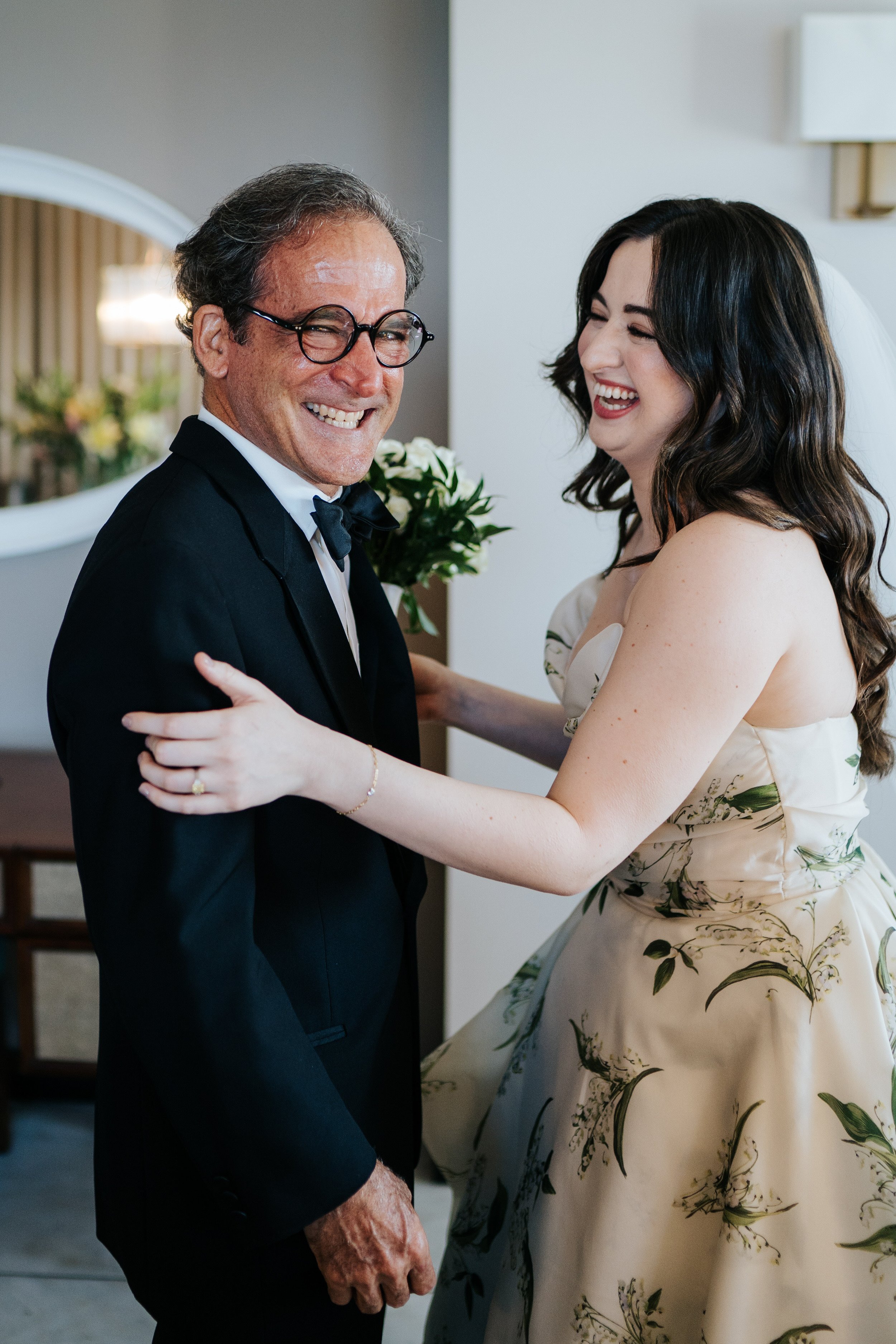 Bride and her dad share a moment before the wedding ceremony as bride embraces him and he smiles at camera